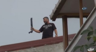 Въоръжен мъж стреля с пушка от покрив на сграда в